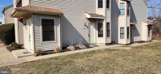 exterior space with a shingled roof and a yard