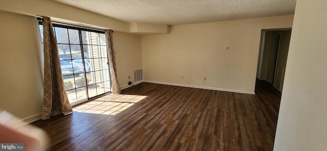 unfurnished room with visible vents, baseboards, dark wood finished floors, and a textured ceiling