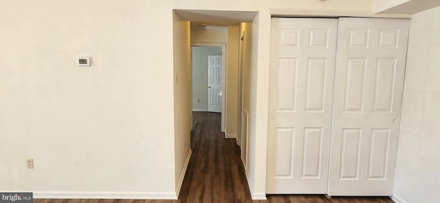 corridor featuring dark wood finished floors and baseboards