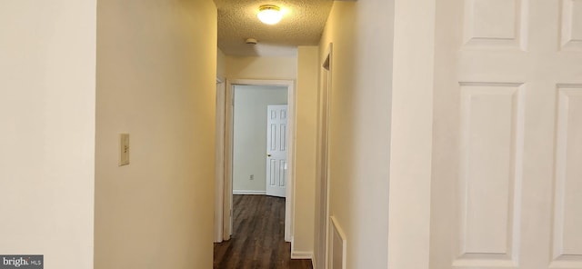 hall featuring a textured ceiling and dark wood-style flooring