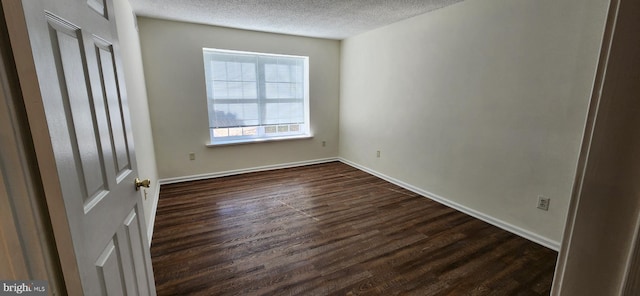 spare room featuring dark wood finished floors, a textured ceiling, and baseboards