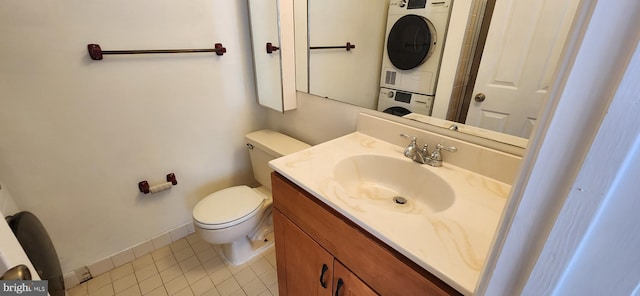 bathroom with toilet, stacked washer / dryer, vanity, baseboards, and tile patterned floors