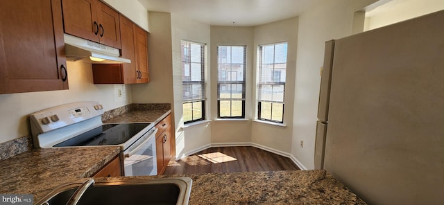 kitchen with dark wood finished floors, brown cabinetry, freestanding refrigerator, white electric range, and under cabinet range hood