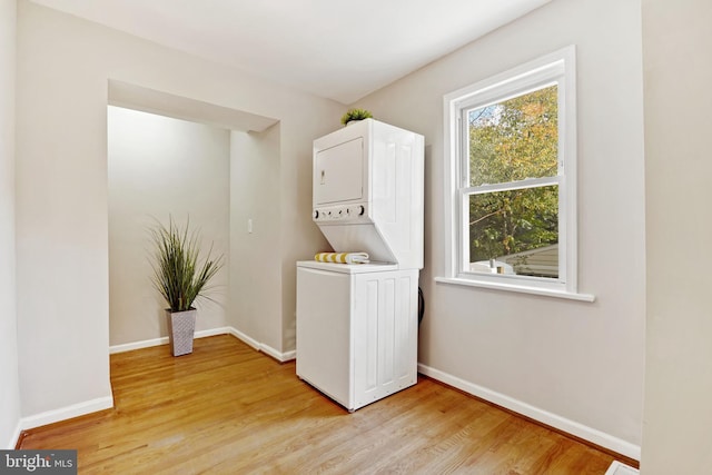 laundry area featuring light wood finished floors, baseboards, and stacked washer / drying machine