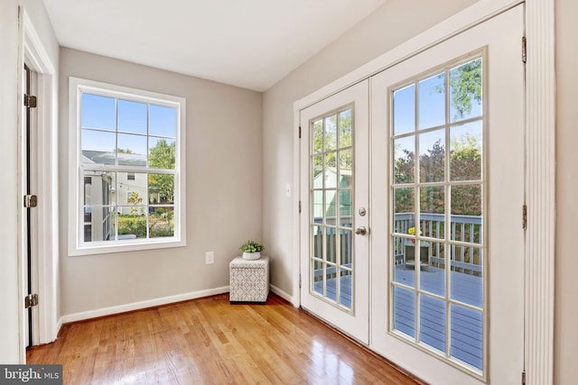 doorway to outside featuring light wood finished floors, french doors, plenty of natural light, and baseboards