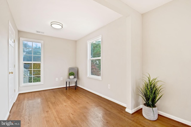 unfurnished room featuring wood finished floors, visible vents, and baseboards