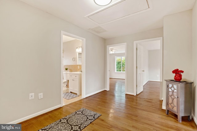 interior space with light wood-type flooring, attic access, baseboards, and a sink