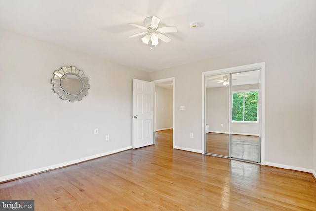 unfurnished bedroom featuring a closet, wood finished floors, a ceiling fan, and baseboards