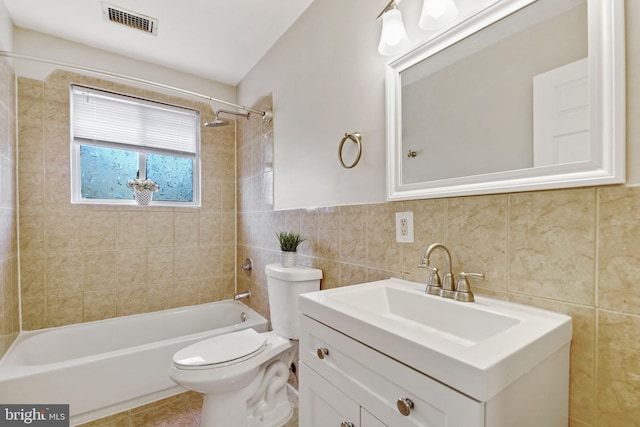 full bathroom with toilet, vanity, visible vents, tile walls, and washtub / shower combination