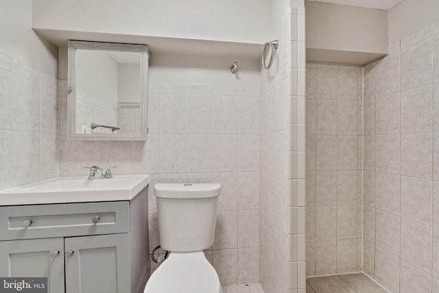 full bath featuring toilet, vanity, and tile walls