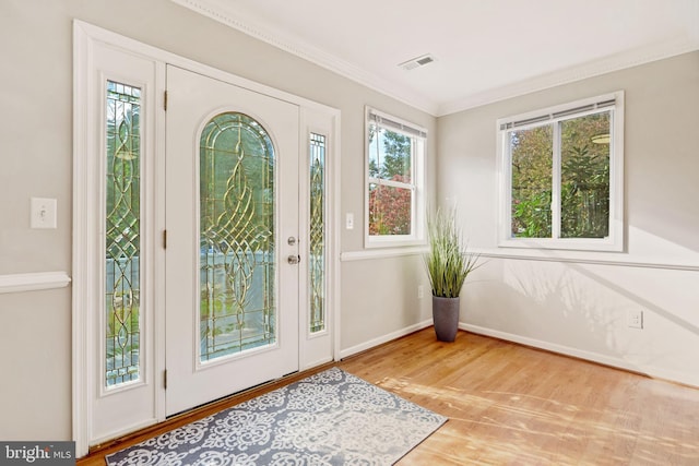 foyer entrance featuring baseboards, visible vents, crown molding, and wood finished floors