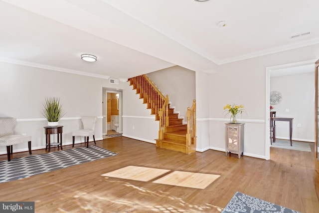 living area with stairs, wood finished floors, visible vents, and crown molding