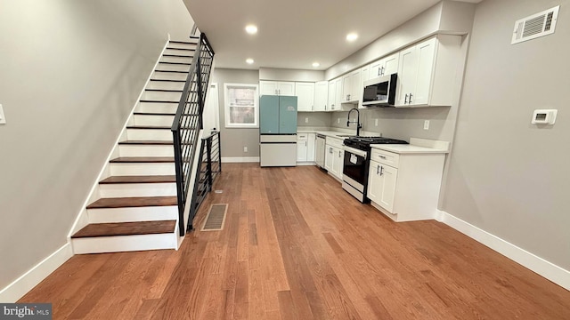 kitchen with appliances with stainless steel finishes, light wood-type flooring, visible vents, and a sink