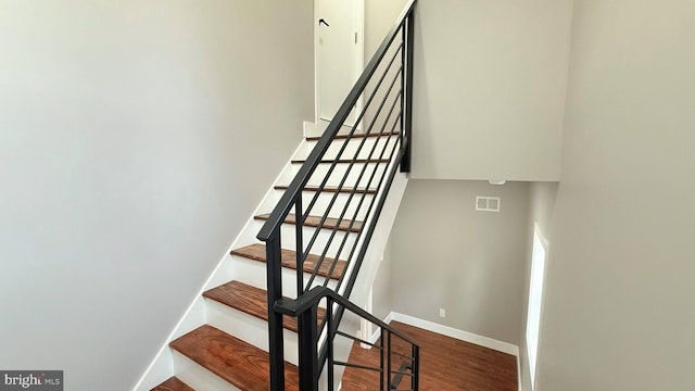 staircase with visible vents, baseboards, and wood finished floors