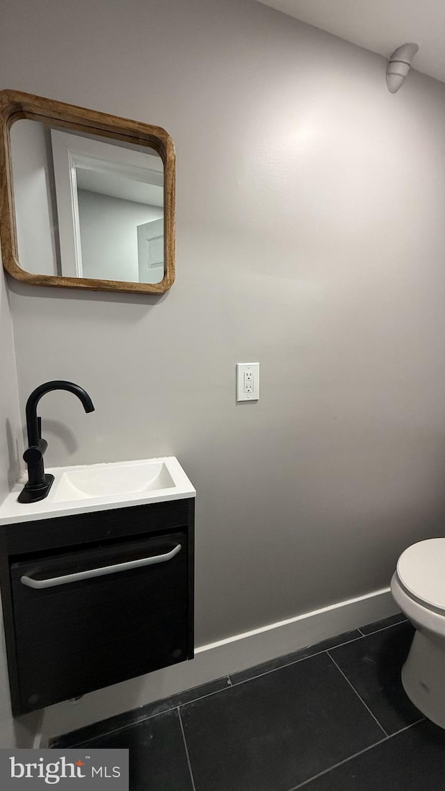 half bath featuring toilet, baseboards, vanity, and tile patterned floors