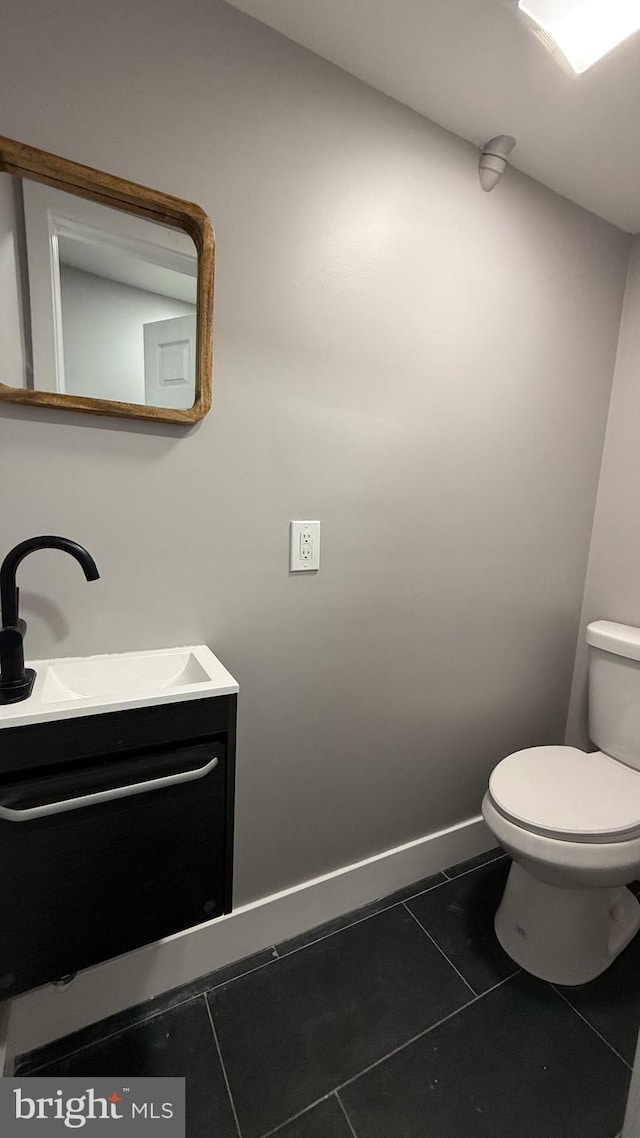 bathroom with toilet, tile patterned floors, baseboards, and vanity