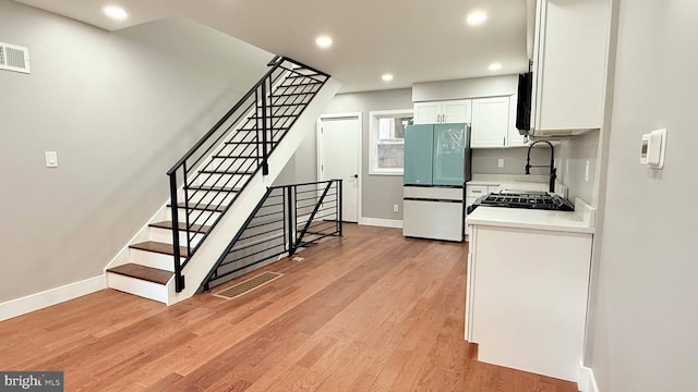 kitchen featuring light countertops, visible vents, light wood-style floors, freestanding refrigerator, and white cabinetry