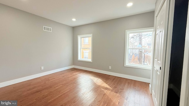 spare room with a healthy amount of sunlight, light wood-type flooring, visible vents, and baseboards