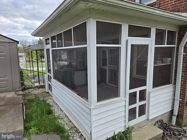 view of home's exterior with a sunroom, brick siding, and fence