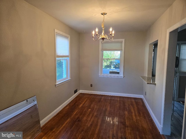 unfurnished dining area with dark wood-style floors, a chandelier, visible vents, and baseboards