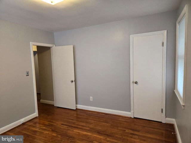 unfurnished bedroom featuring dark wood-style floors and baseboards