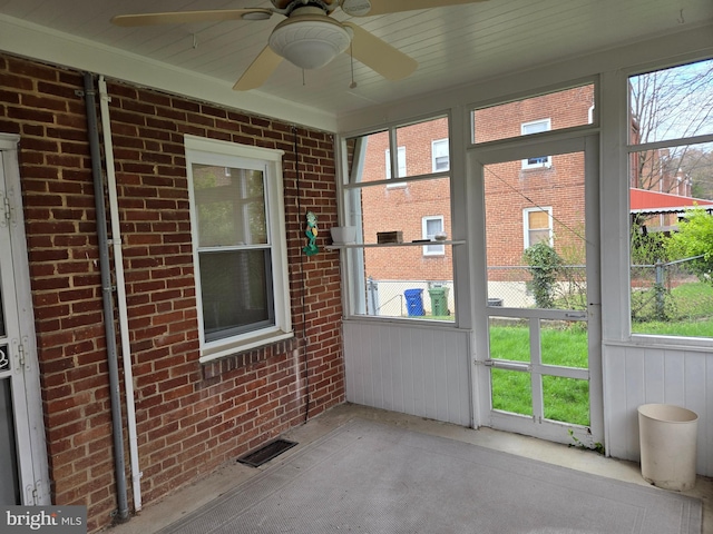 unfurnished sunroom featuring a ceiling fan, a healthy amount of sunlight, and visible vents