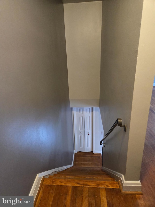 staircase featuring baseboards and wood finished floors