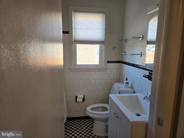 bathroom with tile walls, wainscoting, vanity, and toilet