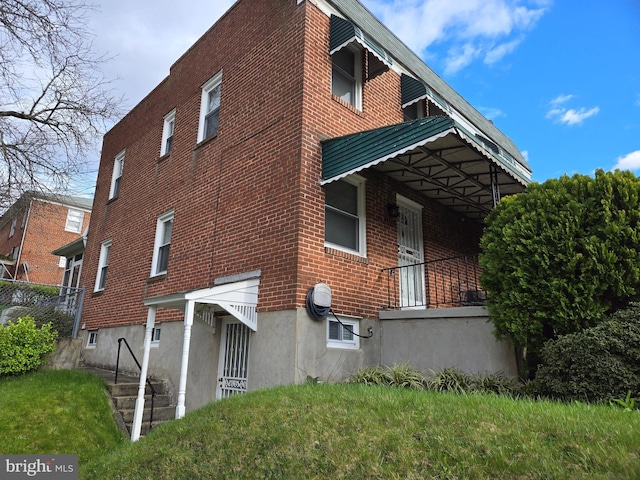 view of side of home with a yard and brick siding