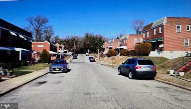 view of road with sidewalks, a residential view, and curbs