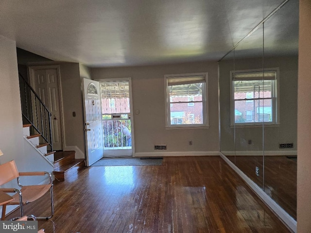 entrance foyer with stairway, dark wood finished floors, and baseboards