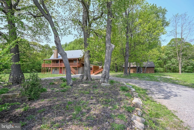 view of front of house featuring a chimney, driveway, and a deck