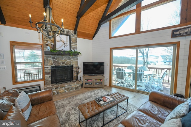 living room featuring a stone fireplace, beamed ceiling, wooden ceiling, and wood finished floors