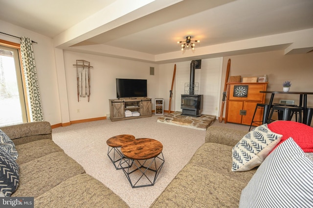 carpeted living room with a wood stove, baseboards, and a tray ceiling