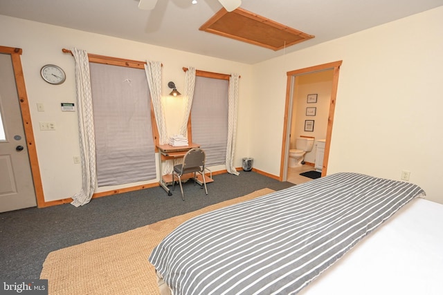 bedroom with dark carpet, attic access, a ceiling fan, ensuite bath, and baseboards