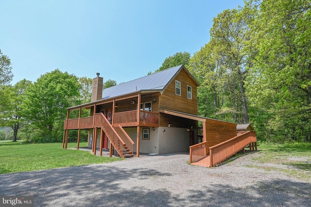 view of front facade featuring a chimney, stairway, metal roof, a wooden deck, and a front lawn