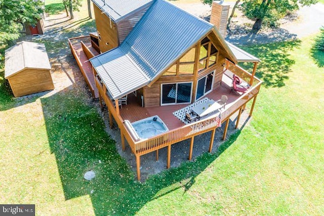 back of property featuring a lawn, a chimney, metal roof, an outbuilding, and a wooden deck