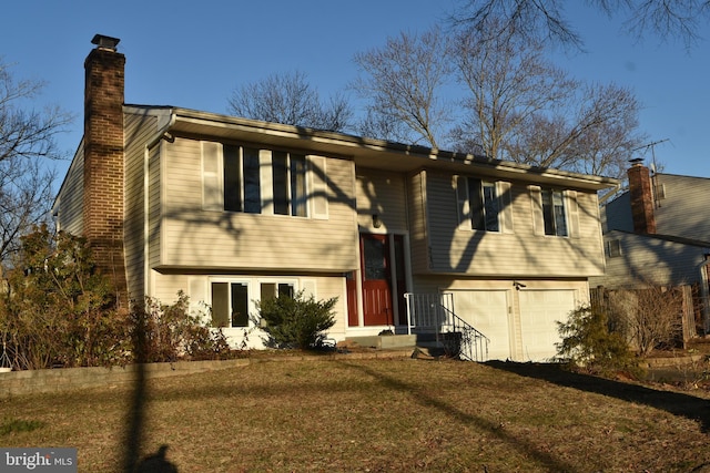 bi-level home with an attached garage, a chimney, and a front yard