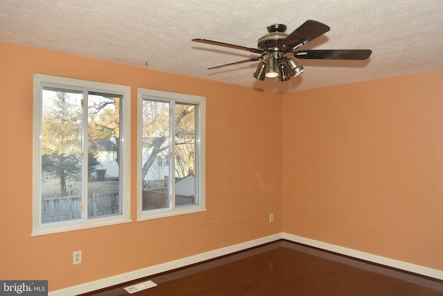 unfurnished room featuring a textured ceiling, ceiling fan, wood finished floors, and baseboards