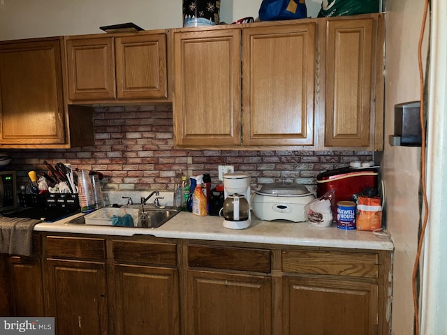 kitchen featuring brown cabinetry, light countertops, and a sink