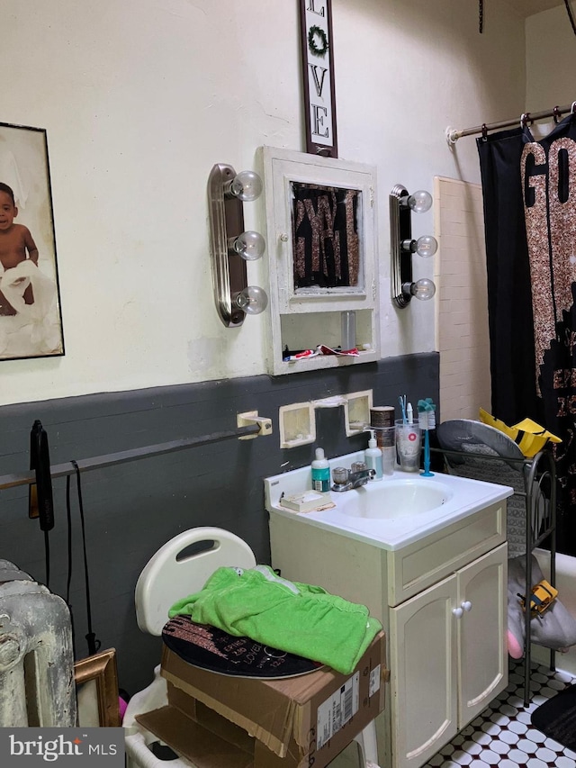 full bath with a shower with curtain, a wainscoted wall, and vanity