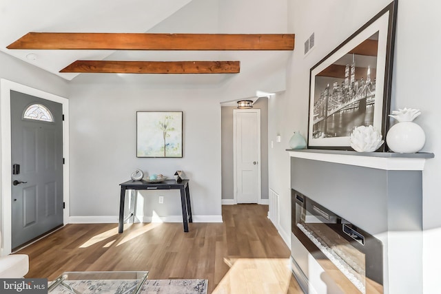 entryway with beamed ceiling, wood finished floors, visible vents, and baseboards