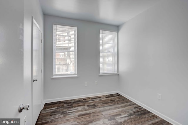 empty room featuring baseboards and dark wood-style flooring