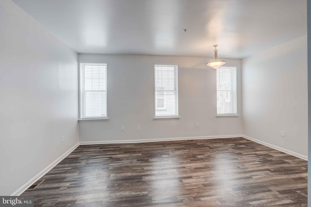 unfurnished room featuring dark wood-type flooring, a healthy amount of sunlight, and baseboards