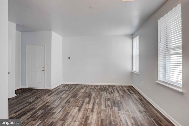 spare room featuring dark wood-style floors and baseboards