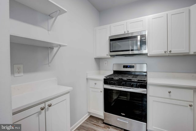 kitchen with light wood finished floors, light countertops, appliances with stainless steel finishes, and white cabinets