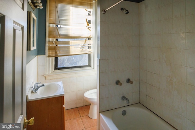 bathroom featuring tile walls, bathing tub / shower combination, toilet, vanity, and tile patterned floors