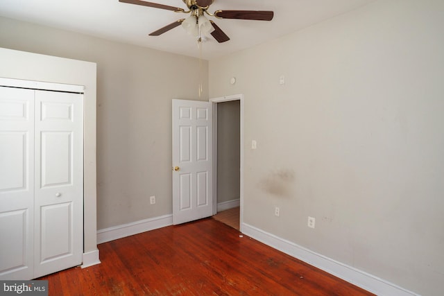 unfurnished bedroom with a closet, dark wood finished floors, baseboards, and ceiling fan