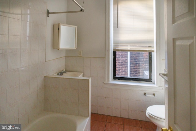 bathroom with toilet, tile patterned flooring, and tile walls