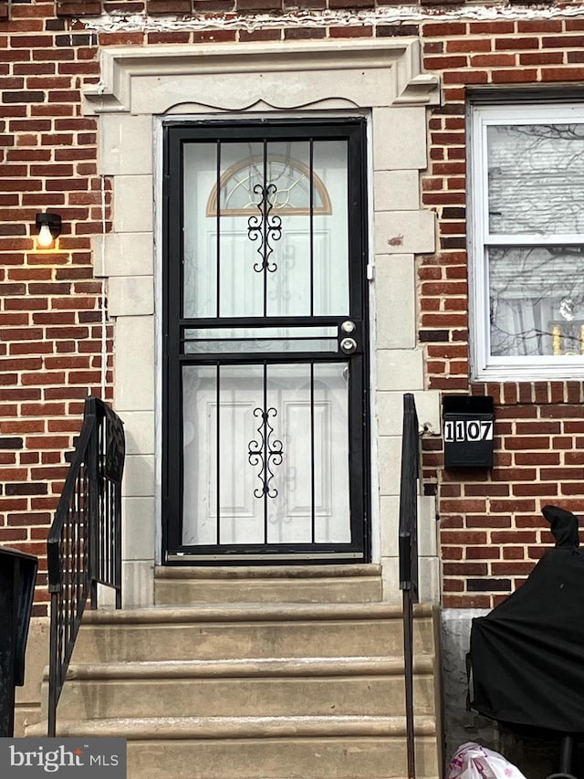 doorway to property featuring brick siding